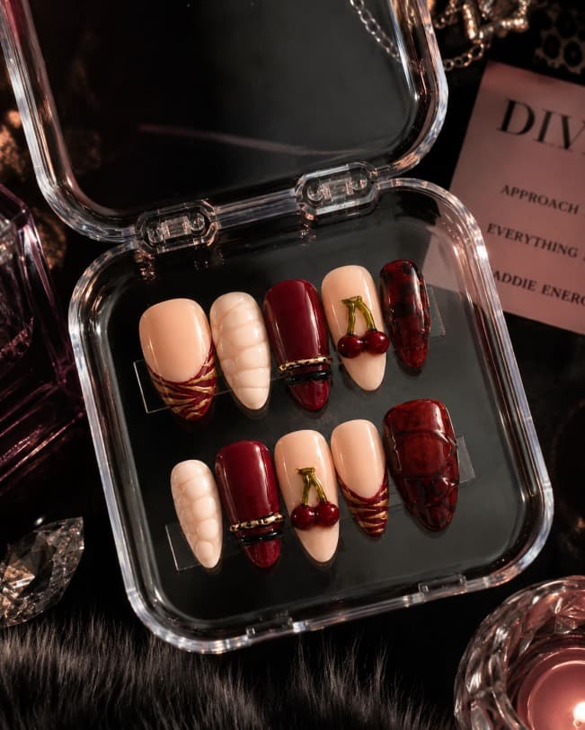Berry Rich — Nude French tips and deep berry-red nails with a 3D cherry charm and gold rings