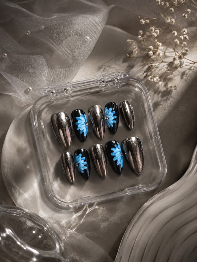Bronze Petals — Mirror-chrome nails alternating with black nails carrying a hand-painted blue daisy