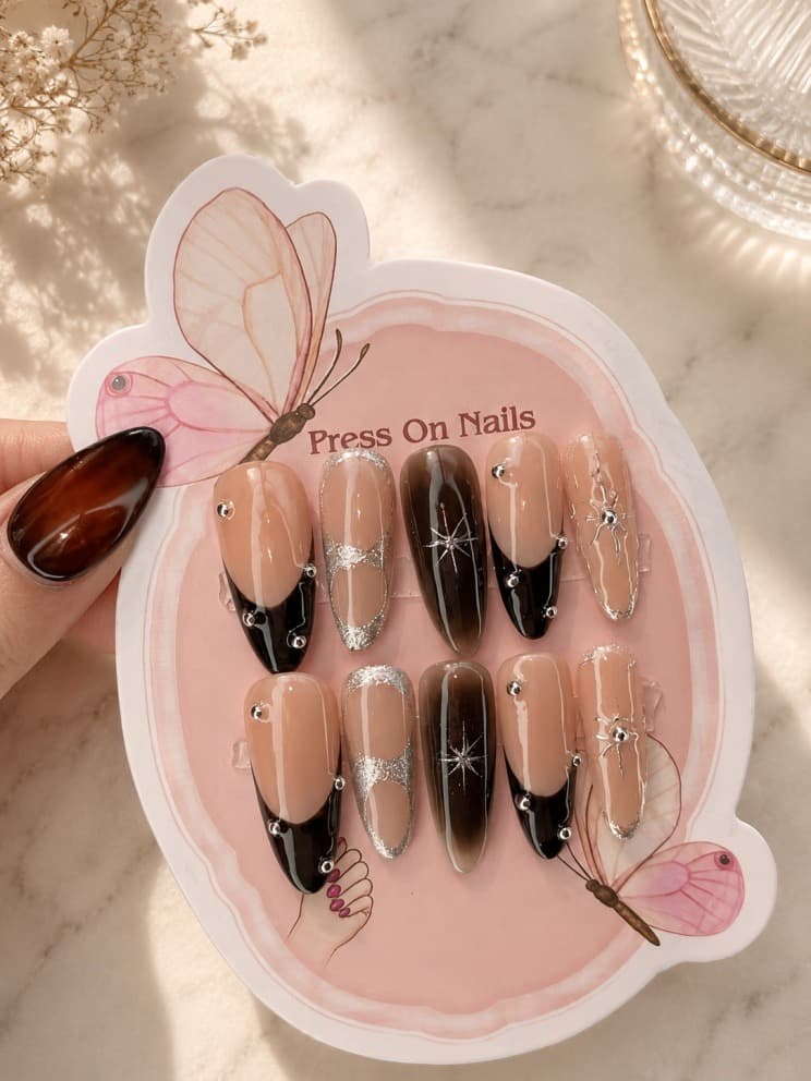 Coastal Fog — Nude-and-black French tips with silver glitter accents and a star charm
