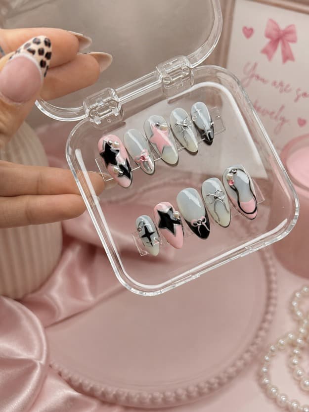 Dark Coquette — Pink and grey nails with black star charms and bow accents