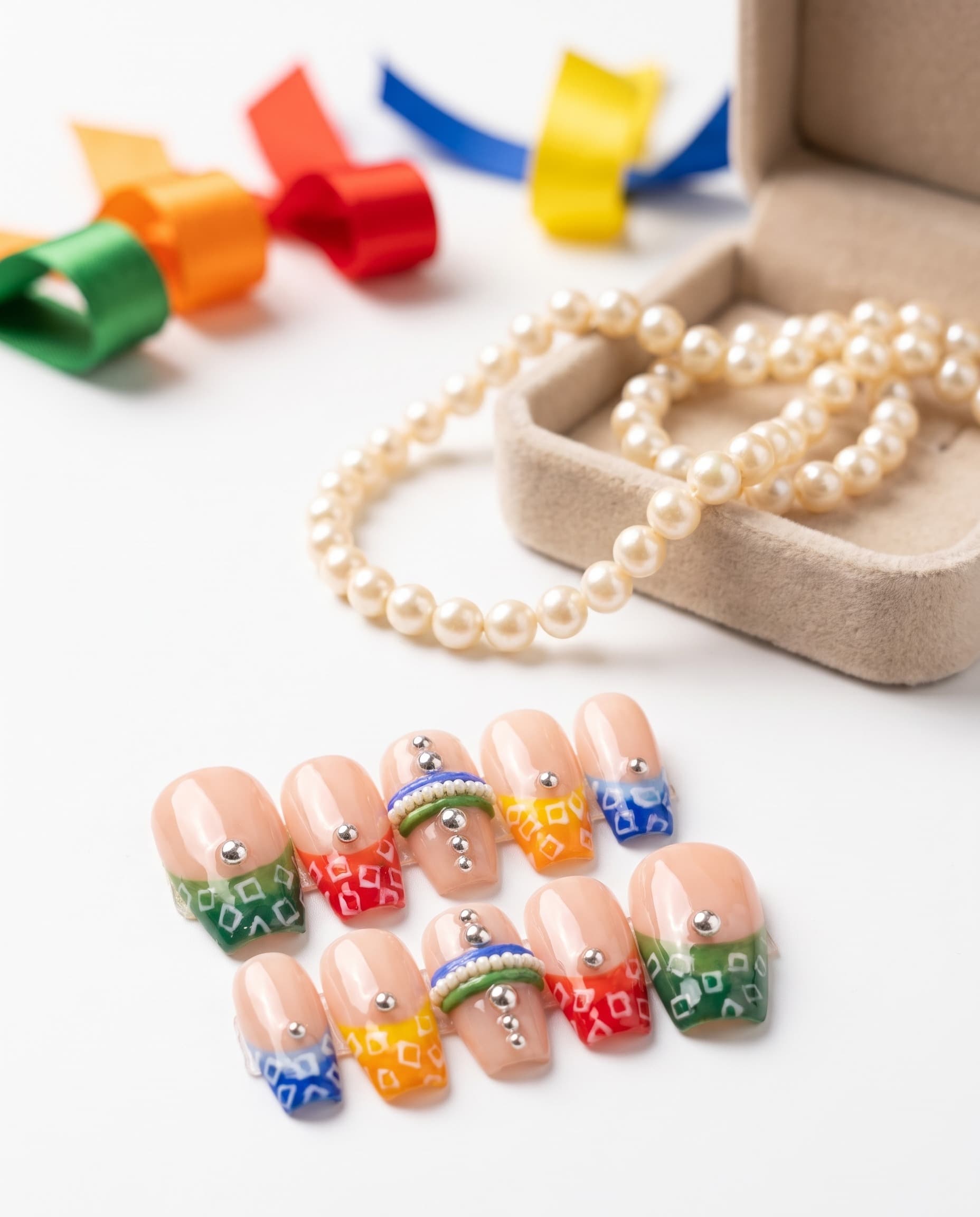 Rang Rasiya — Nude base with a different colored diamond-print tip per nail and a pearl bead-chain accent nail