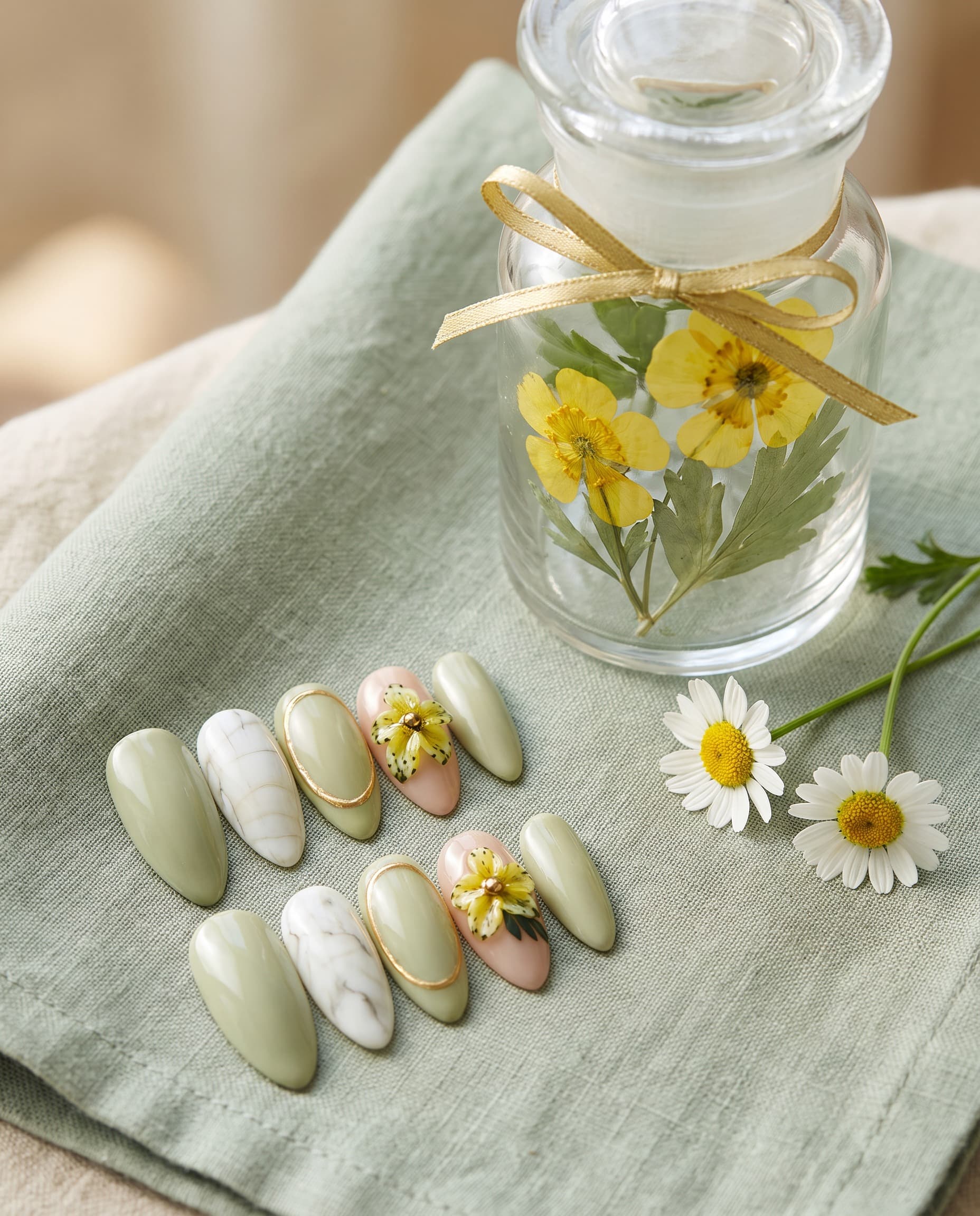 Matcha Blossom — Sage green with white marble, a gold-outlined nail, and a 3D yellow flower